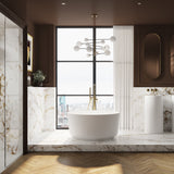 The Godwin stone freestanding soaking tub in a modern London bathroom with brushed brass freestanding bath taps and the Lanyon stone freestanding basin.